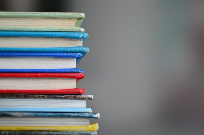 A stack of textbooks against a blurred grey background