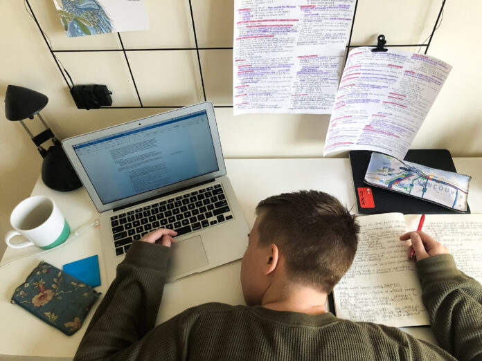 A person face down on a desk fallen asleep with notes scattered all across the desk