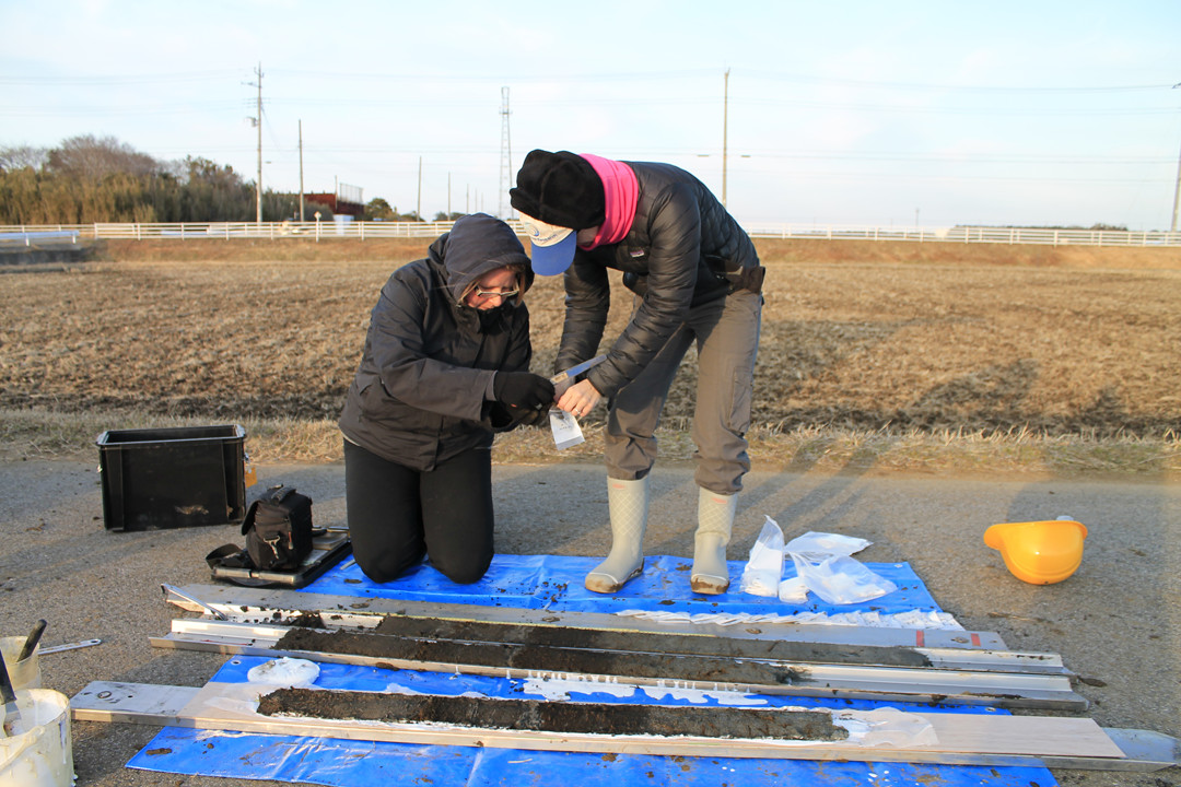 Jessica Pilarczyk on the left and colleague on the right, looking at sediment on a blue tarp