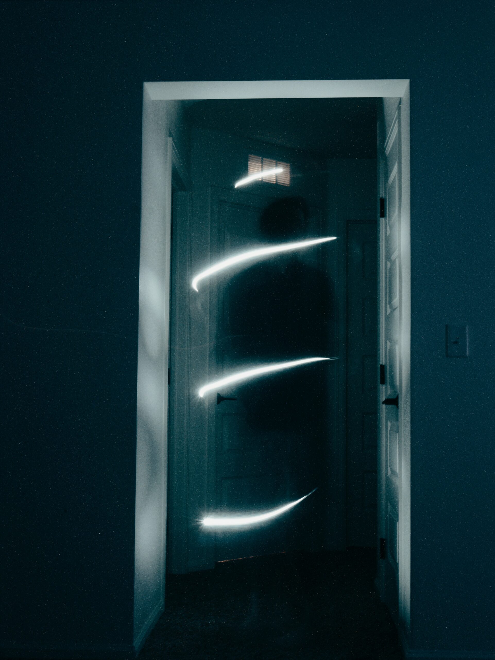 a dark shadow stands in doorway in a spiral of white light