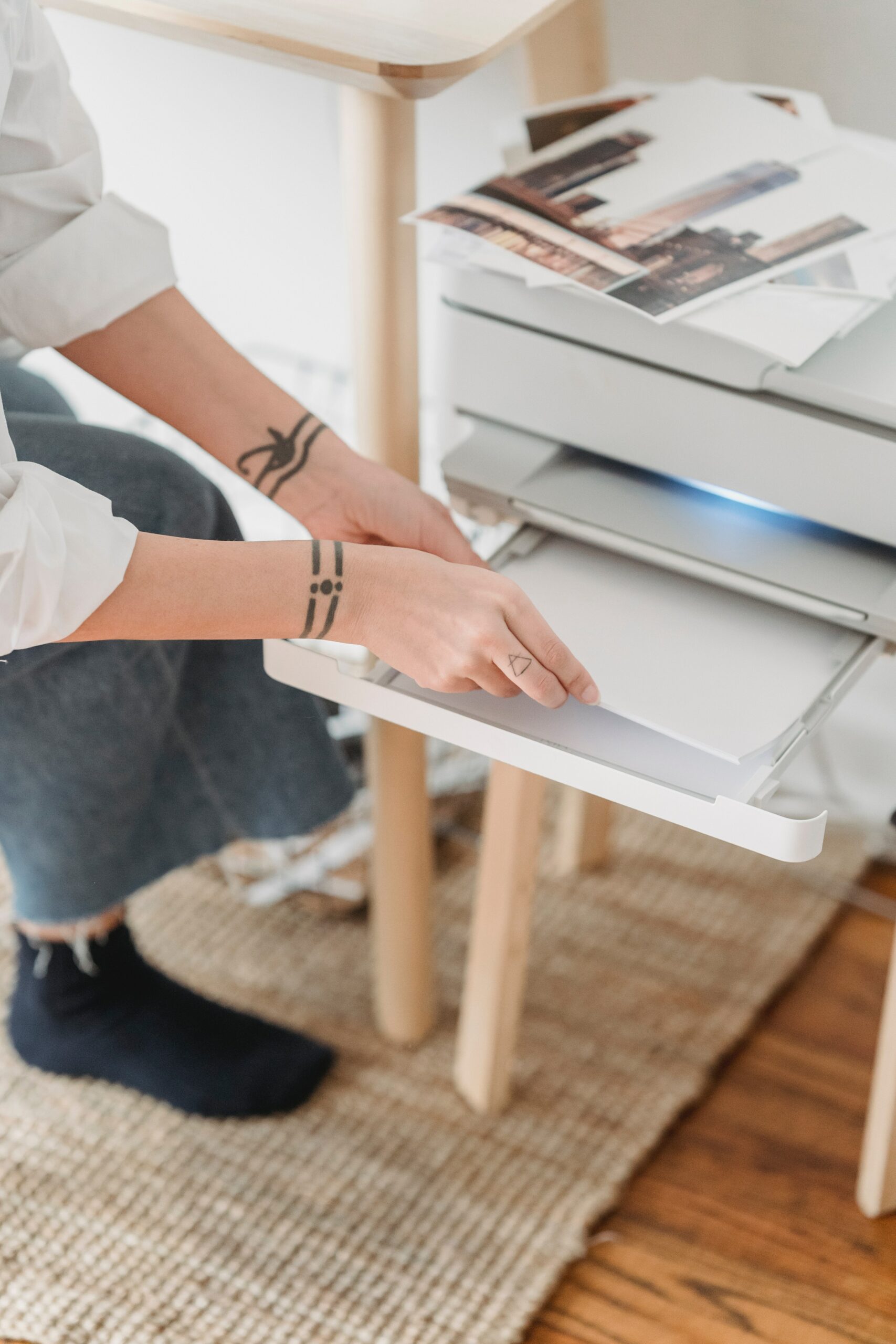 Hands with wrist tattoos grab blank pages from printer