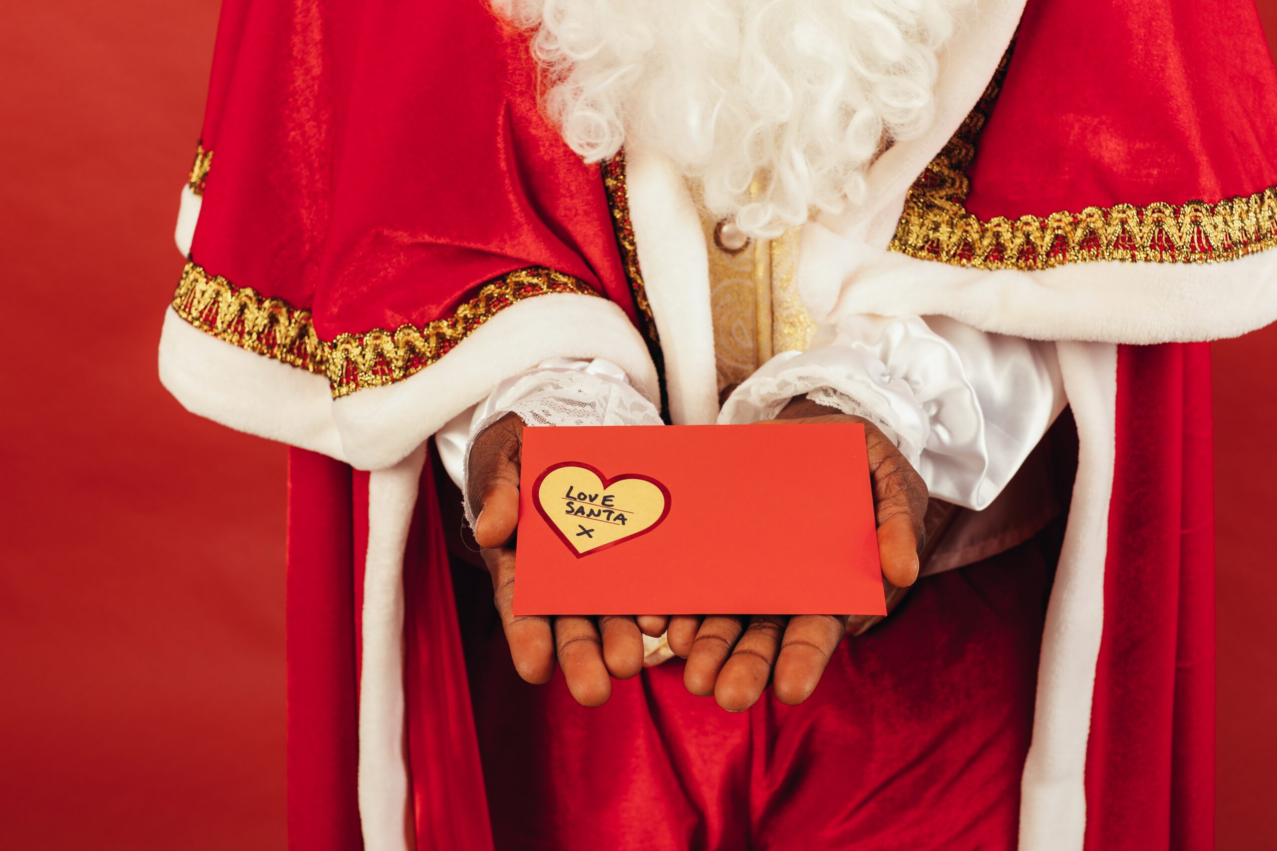 person dressed like Santa Claus holds card labeled "love, Santa"