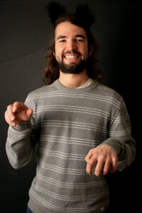 Jacob smiling in regular clothes with hands in playful claw shapes