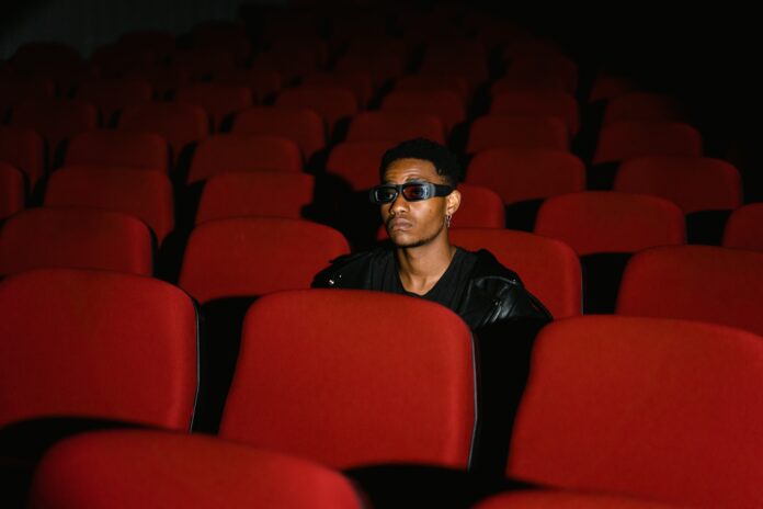 3D sux A guy is sitting in a theatre. He is wearing 3D glasses, and manages to look both skeptical and unimpressed.