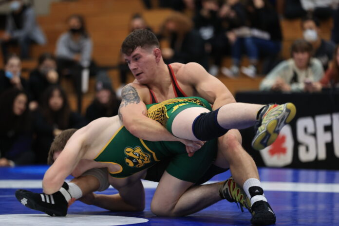 AB9I7604 Logan Nelson grapples an opponent on the floor, with his arms locked around their leg.