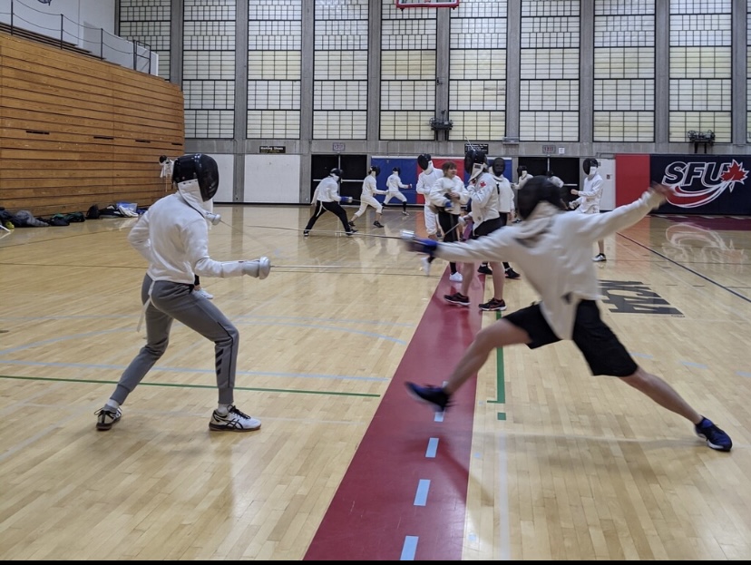 A photo of a member of the SFU fencing team lunging at the other with a foil (sword) in hand.