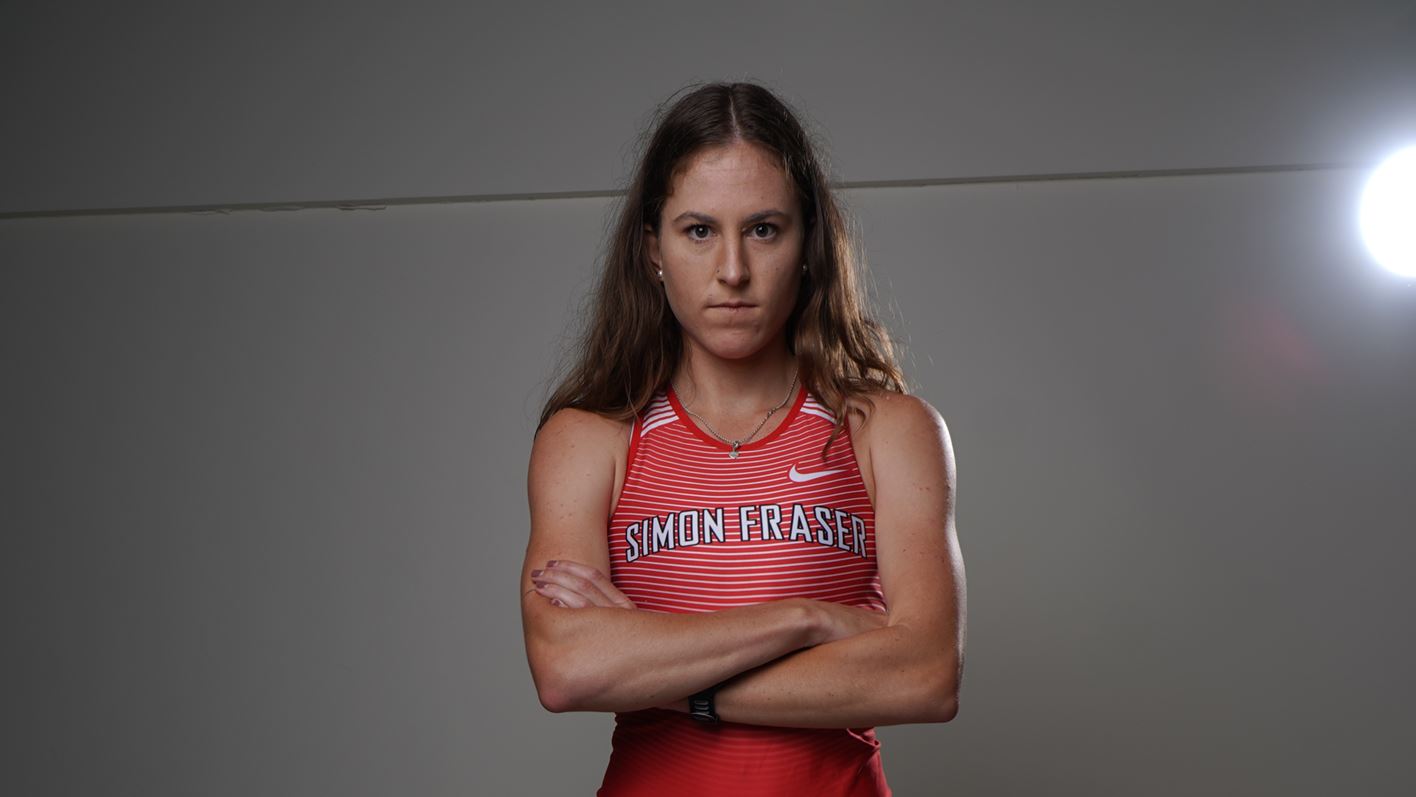 A photo of SFU track runner Alison Andrews-Paul with her arms crossed posing in front of the camera.