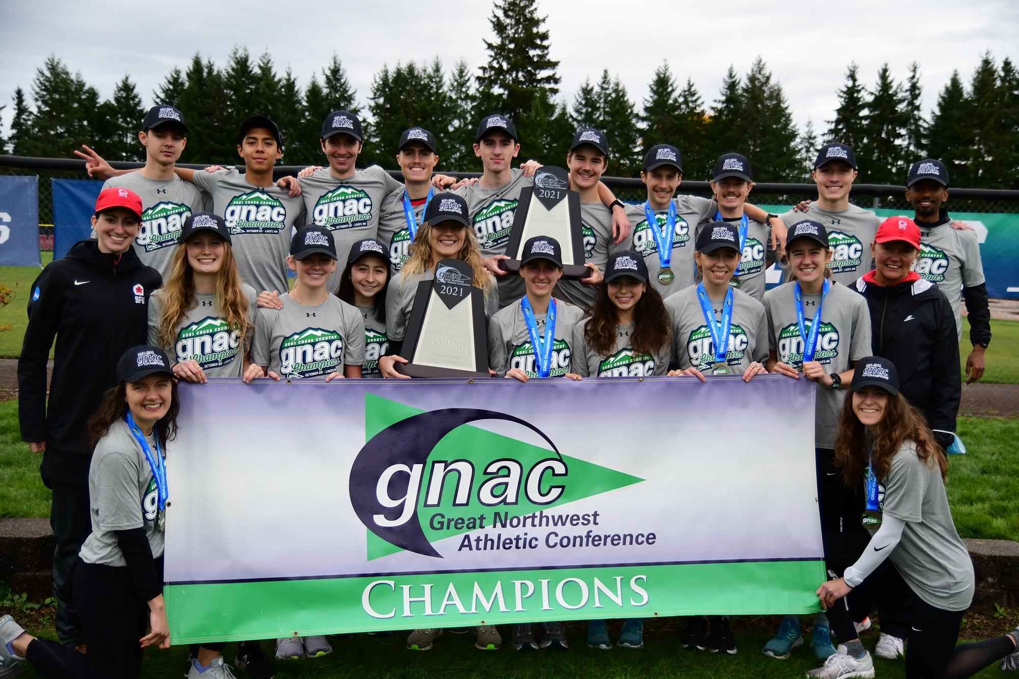 A photo of SFU's cross country team holding the GNAC Championship banner after winning.