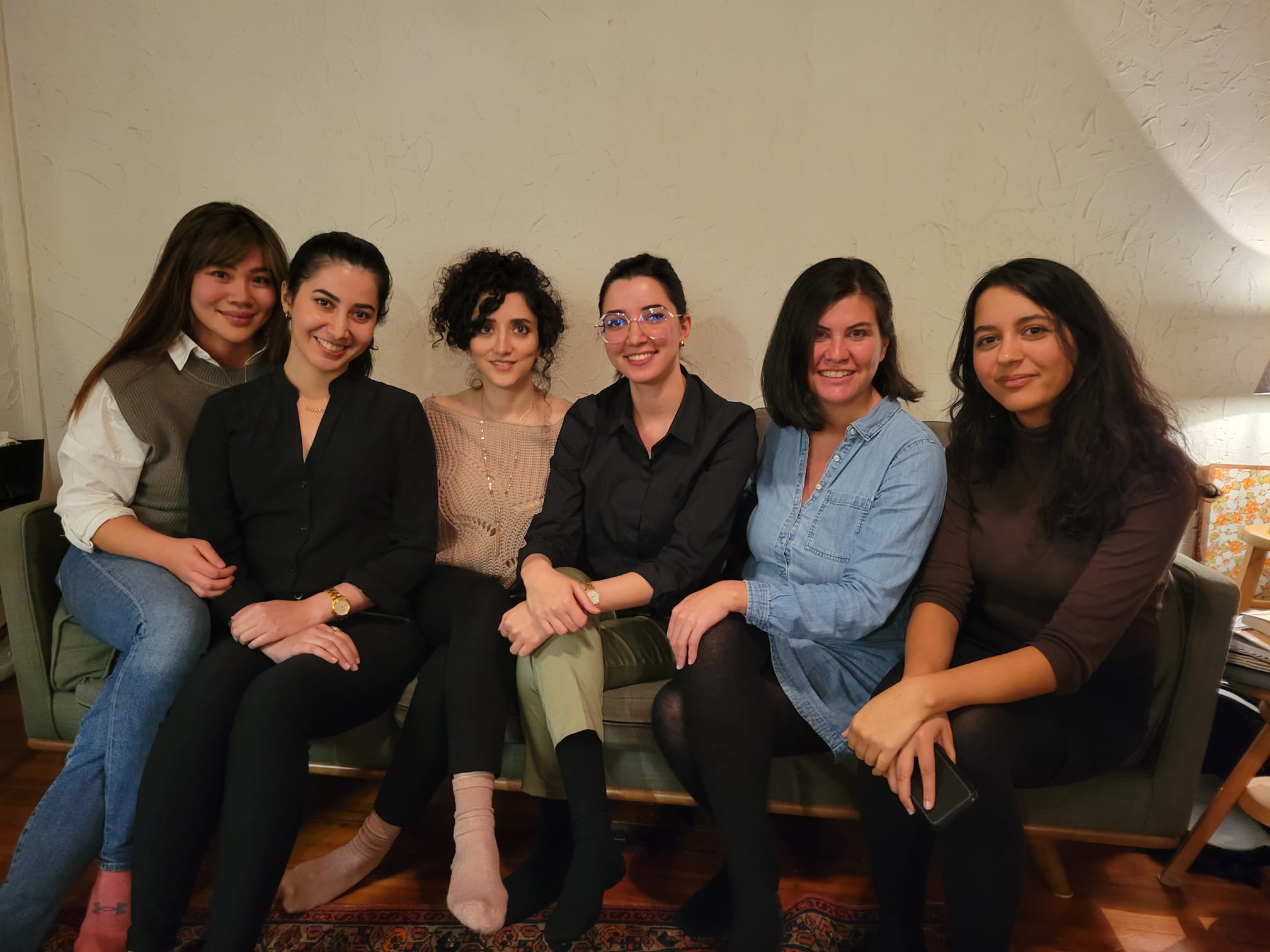 Six women sitting next to each other on a couch