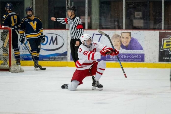 Photo of SFU forward Garret Hilton on one knee celebrating his goal scored against UVIC.