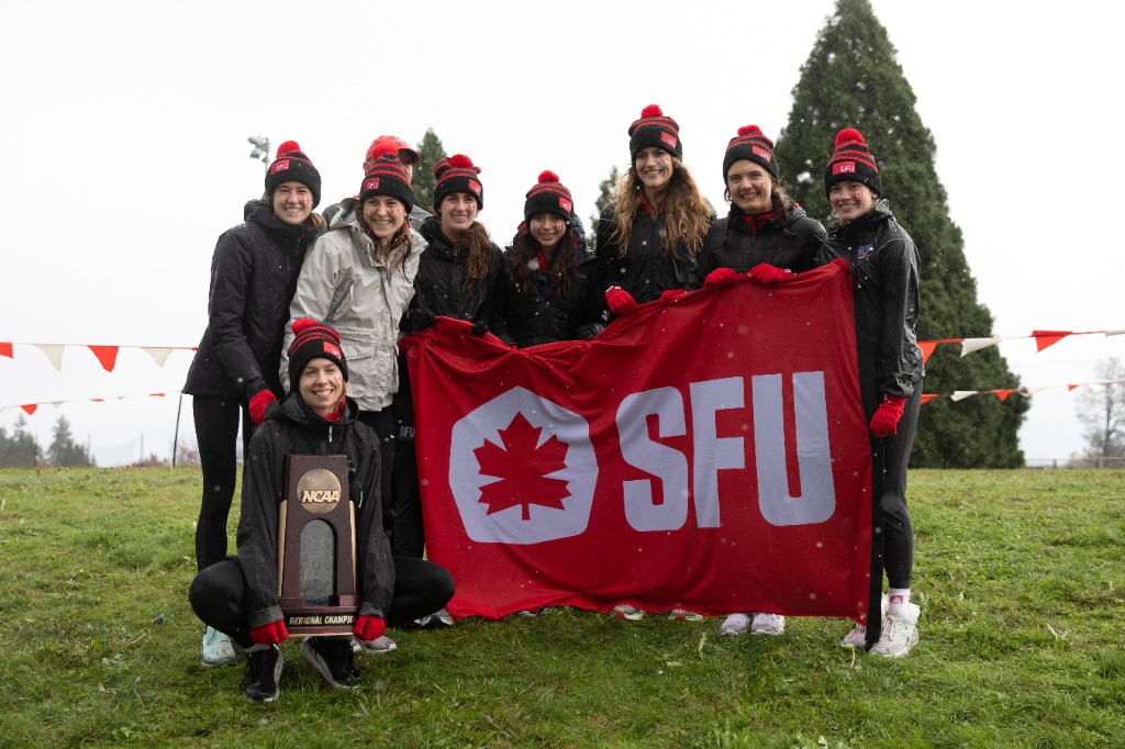 A photo of the women's SFU cross country team holding an SFU banner and Championship after winning Regionals.