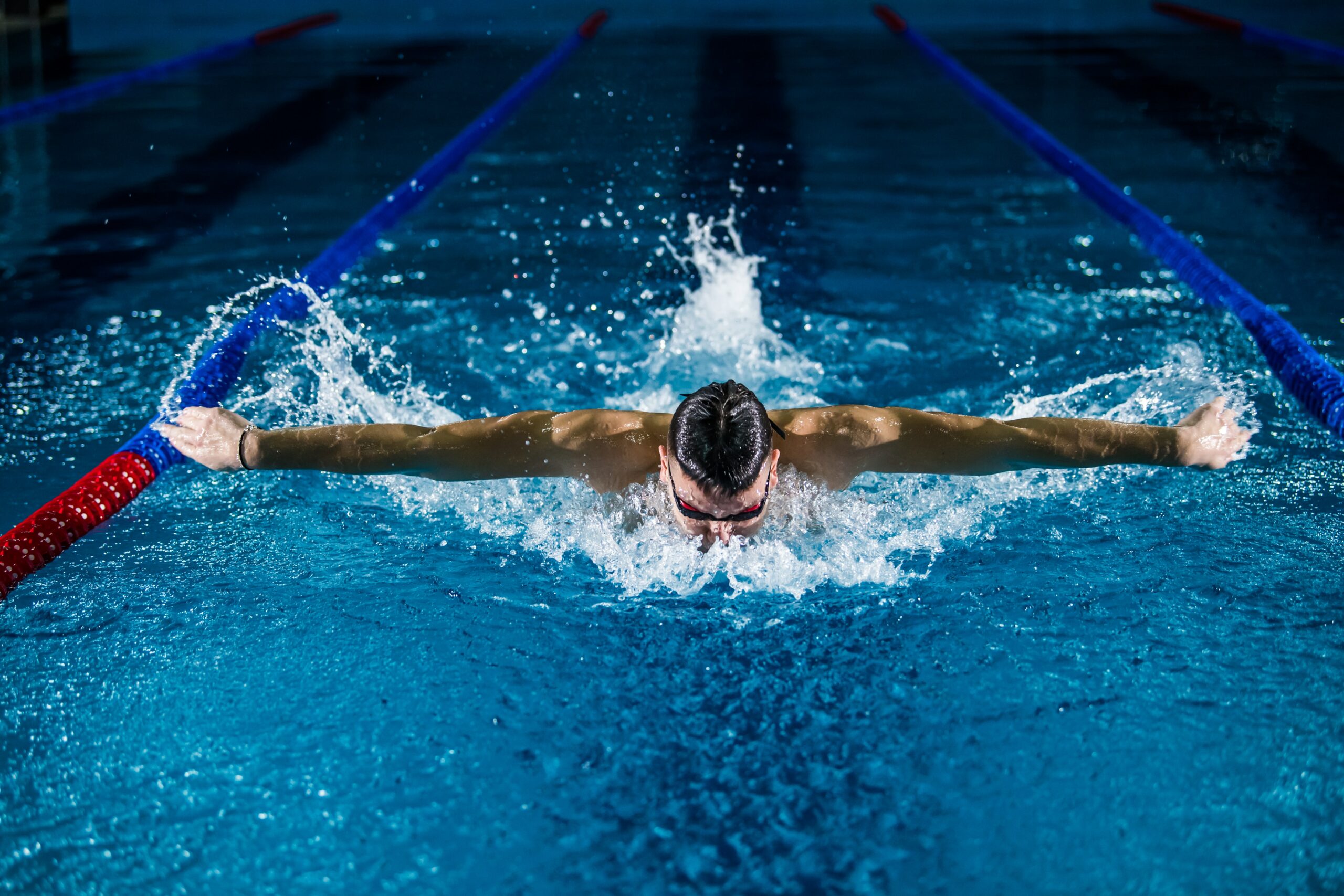 A shot of a swimmer heading back into the water after taking a moment to come up to the surface during a butterfly stroke.