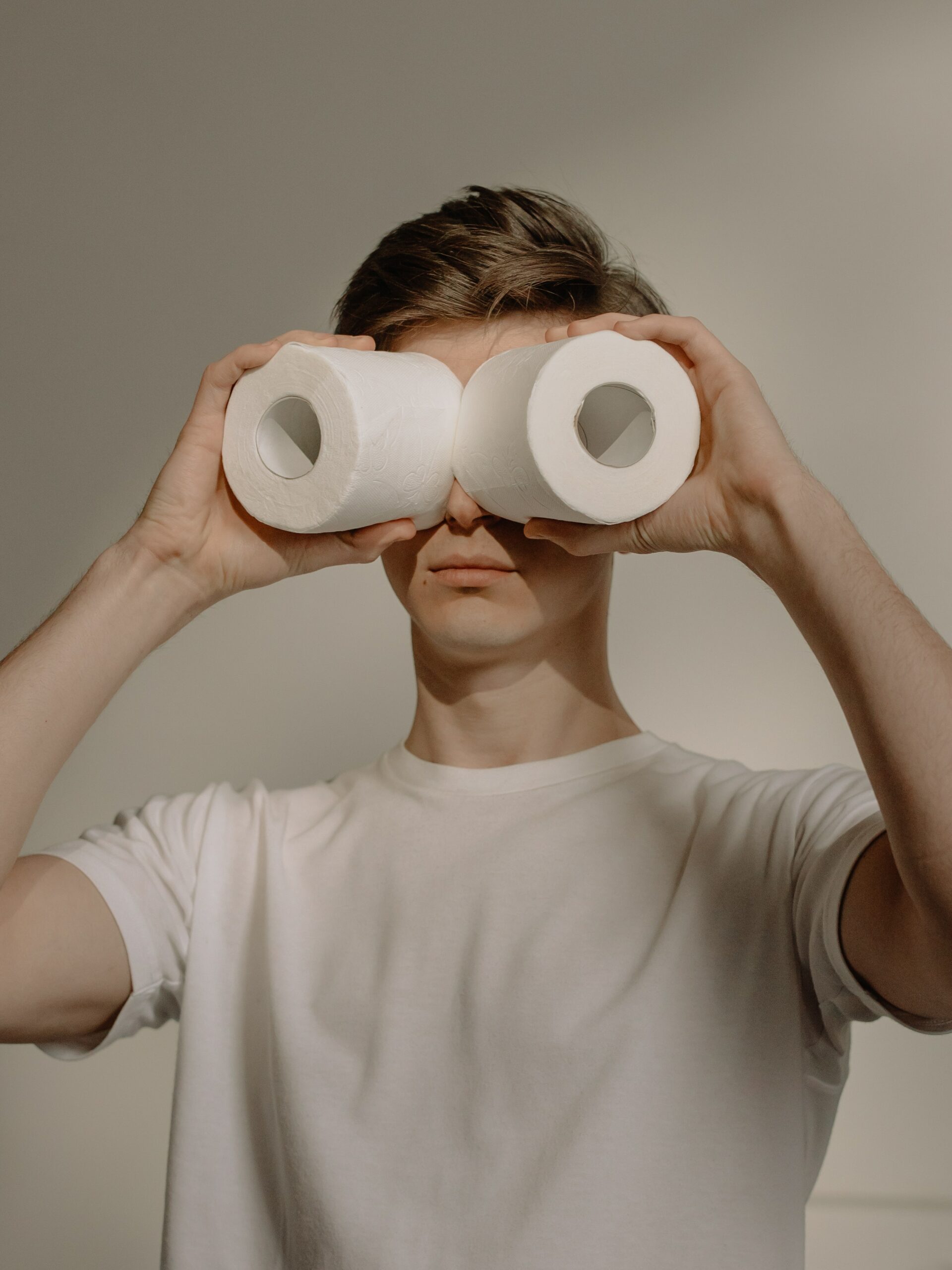 Someone is holding toilet paper rolls over their eyes like binoculars. They are straight-faced, and it’s a very funny-looking photo.
