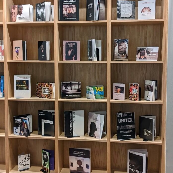 A tall, wooden bookcase filled with self-published books.
