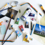 Four accessible ways to make art at home Flatlay photo of a white table full of art supplies — like acrylic paint, pencil crayons, and cardstock — in a variety of colours.