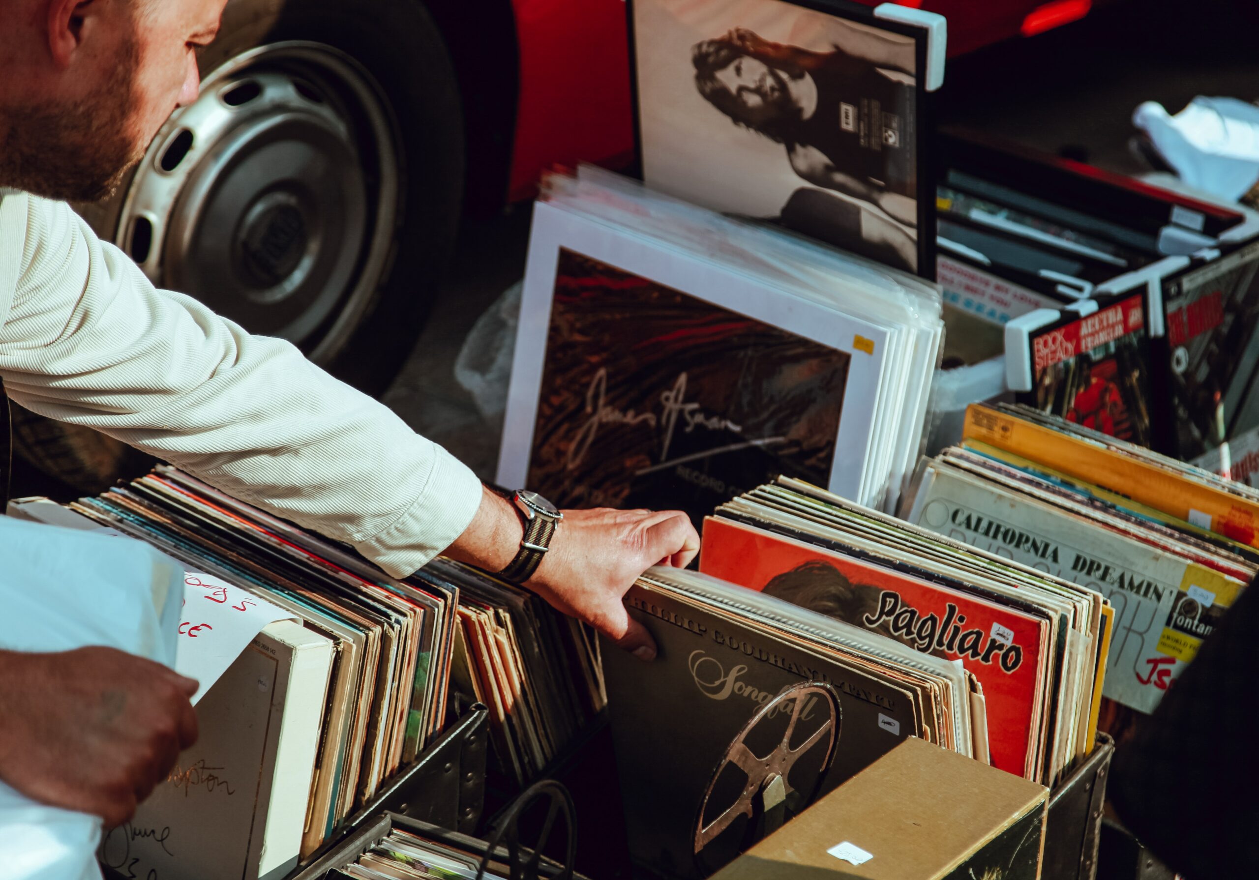 A hand flicks through a collection of vinyl records