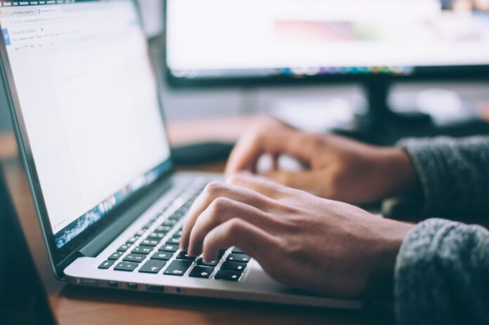 close shot of someone’s hands typing on a laptop