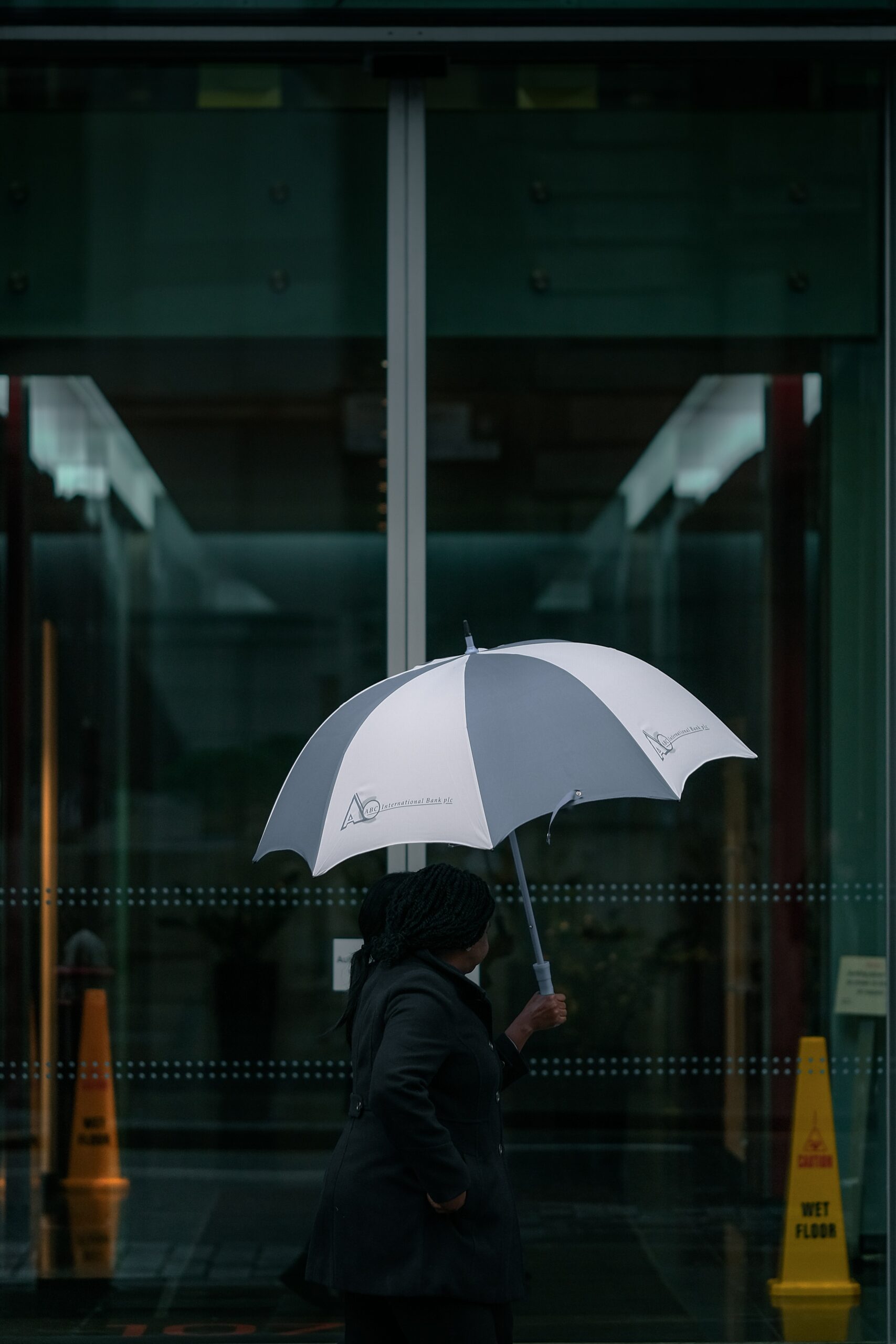 A figure with an open umbrella under an awning