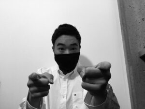 Feng wearing a mask pointing at the camera in black and white
