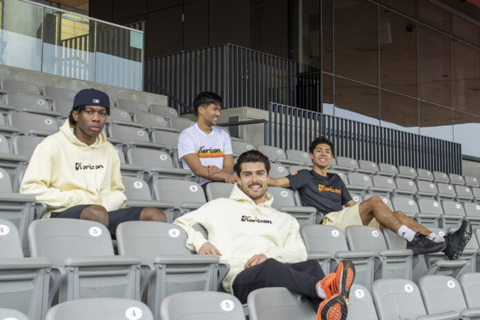 Four members of HorizonTrack posing on grey bleachers.
