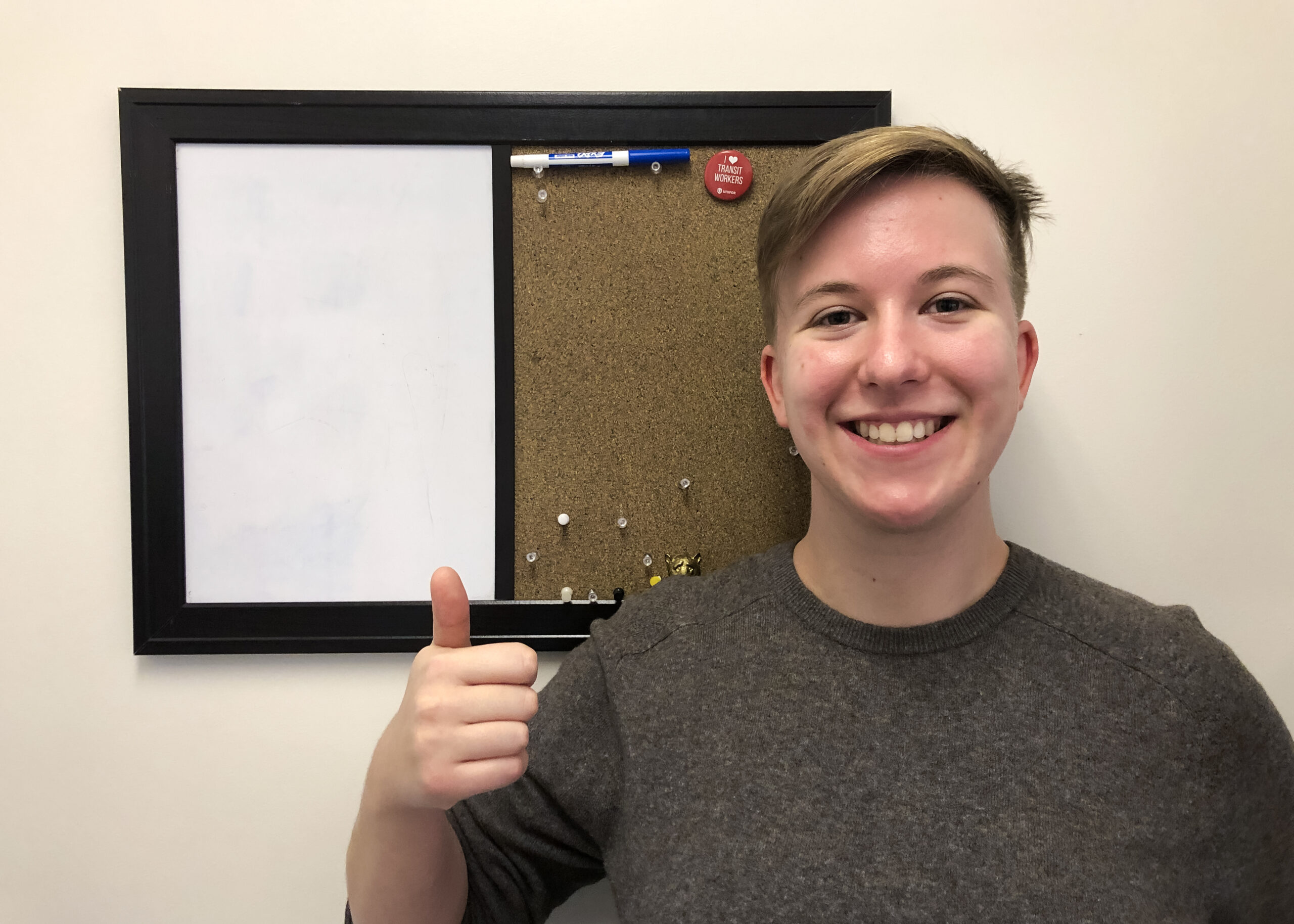 A person giving the thumbs up in front of a whiteboard