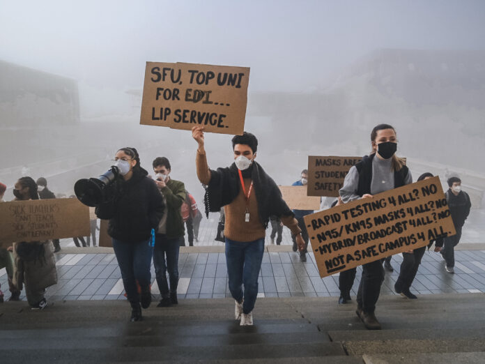 Students walking up Convocation Mall staircase with signs
