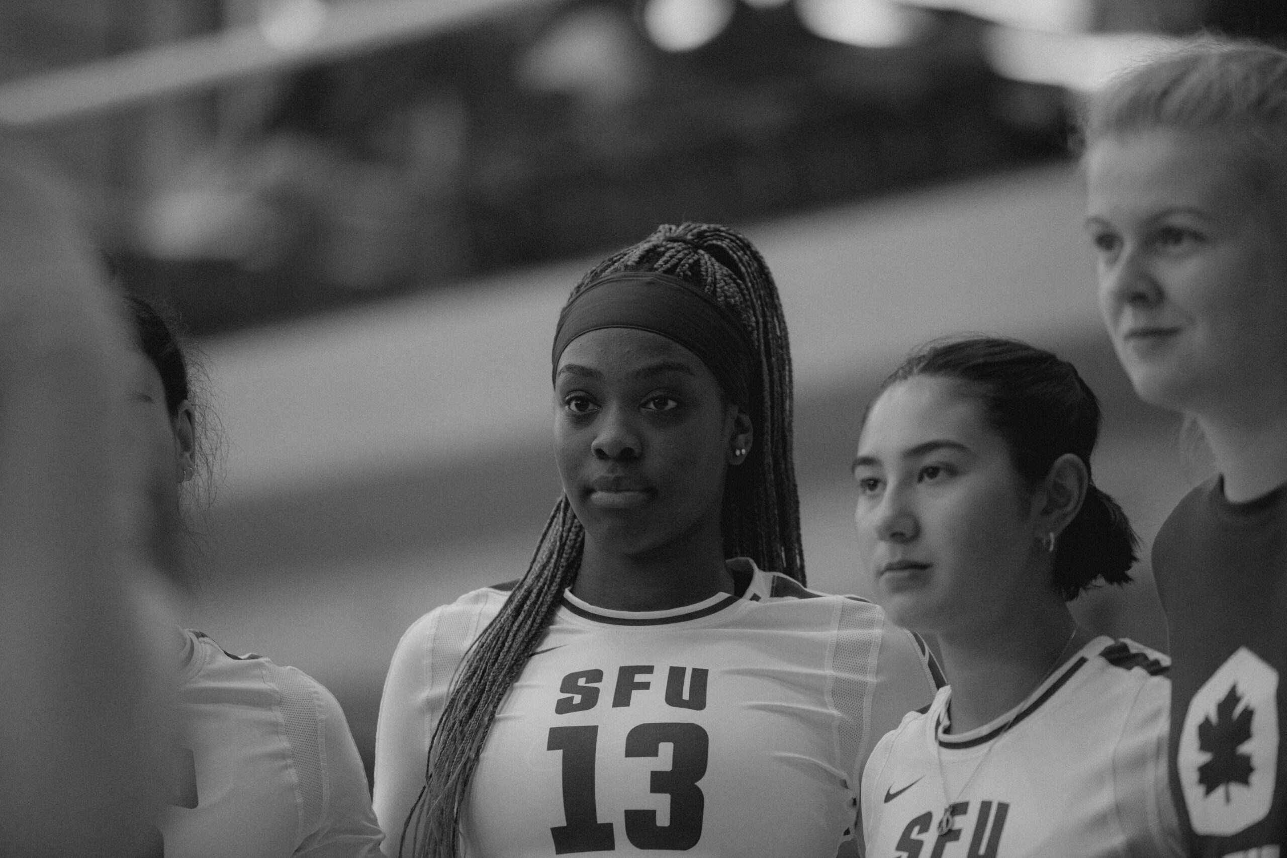 Black and white photo of Ezawa Malish in a huddle with her team.