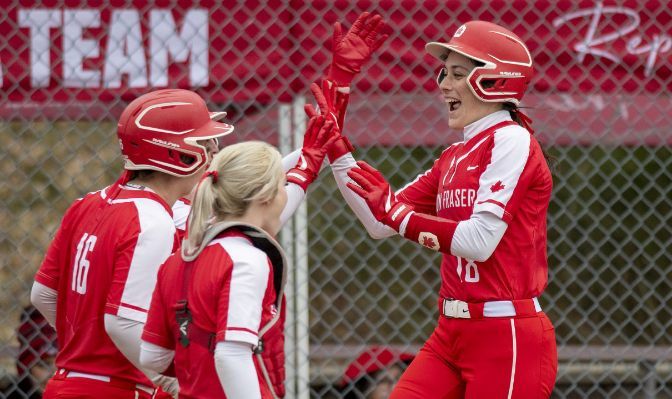 SFU softball members celebrating and high-fiving each other.