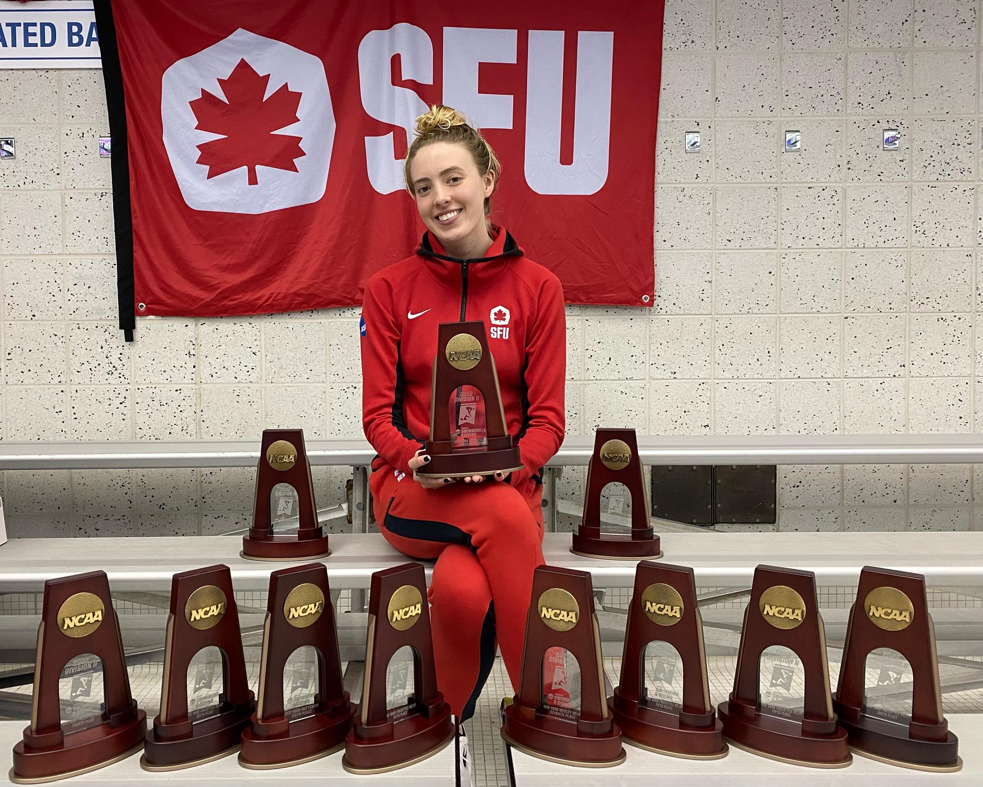 SFU swimmer Kayleigh Sharkey posing with her 11 trophies