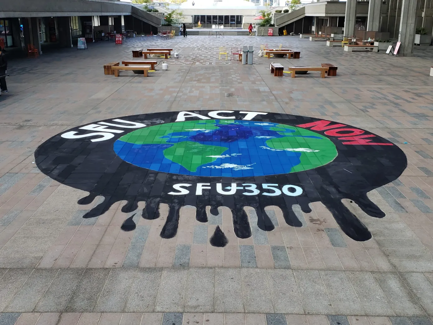 A mural of the world surrounded by oil with the text “SFU act now SFU350” written around it painted on the group