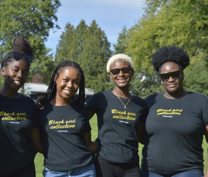 four people standing next to each other and smiling at camera