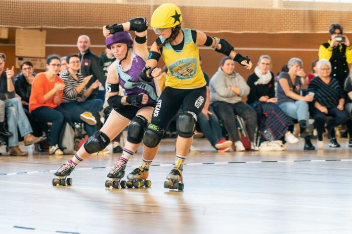 bastien-plu-79tKLlGl2Tg-unsplash (1) Photo of two roller derby women leaning in to hit each other on the track.