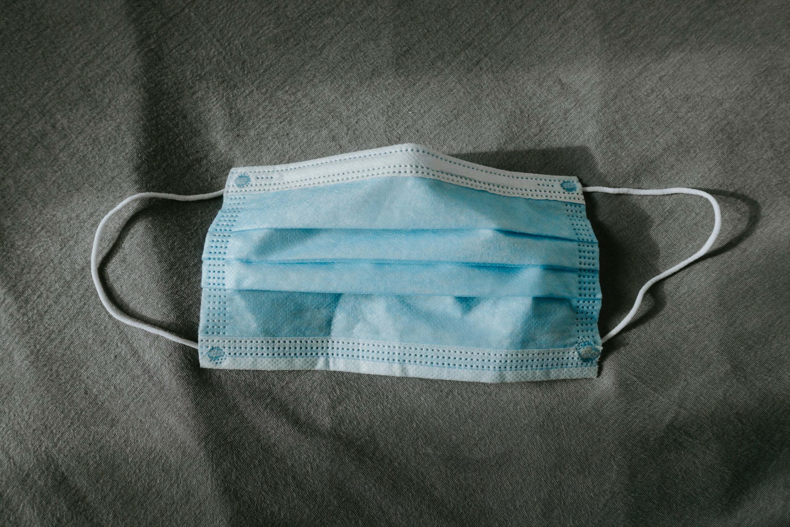 A blue disposable mask on a grey background