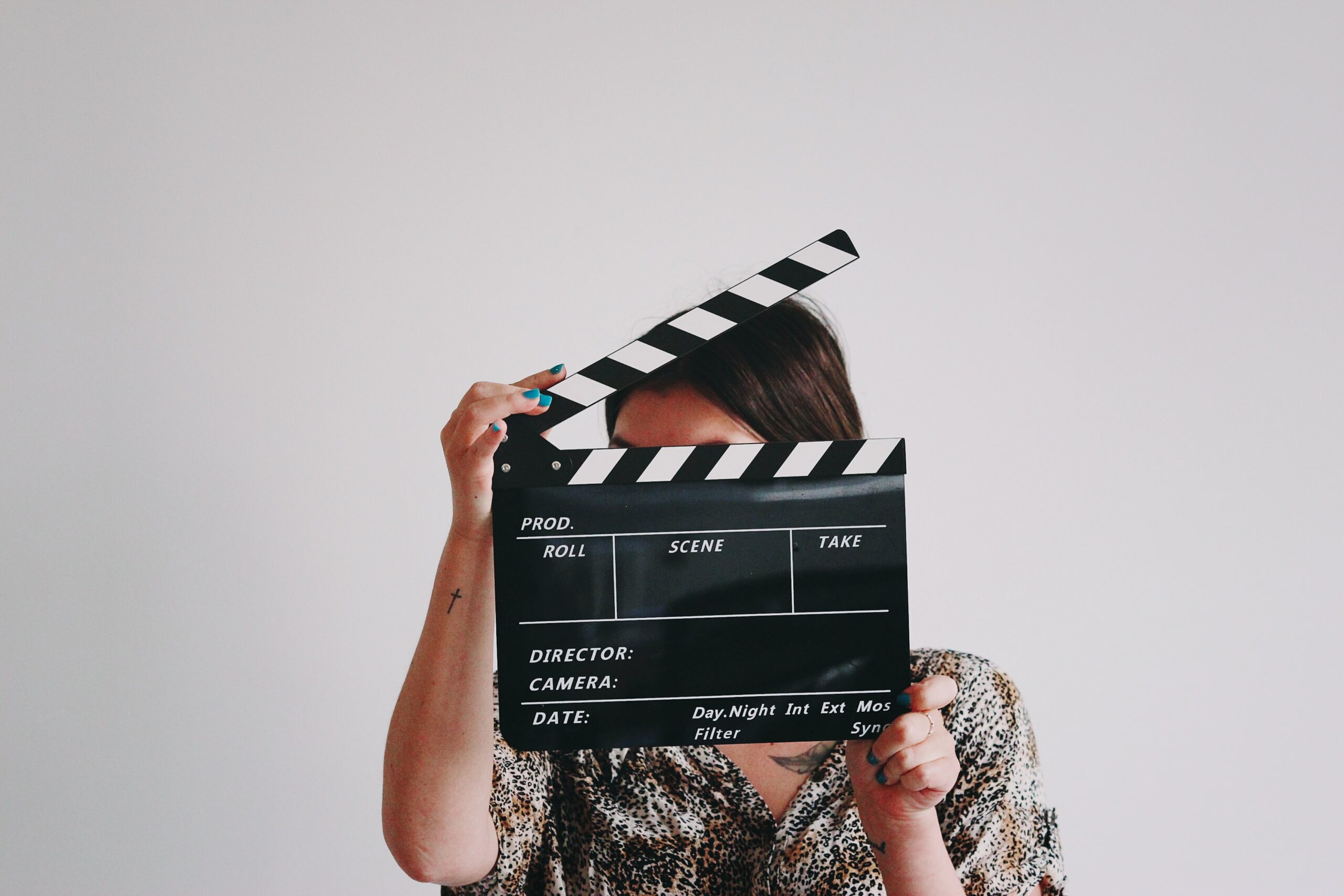 A woman holding a clapboard in front of her face