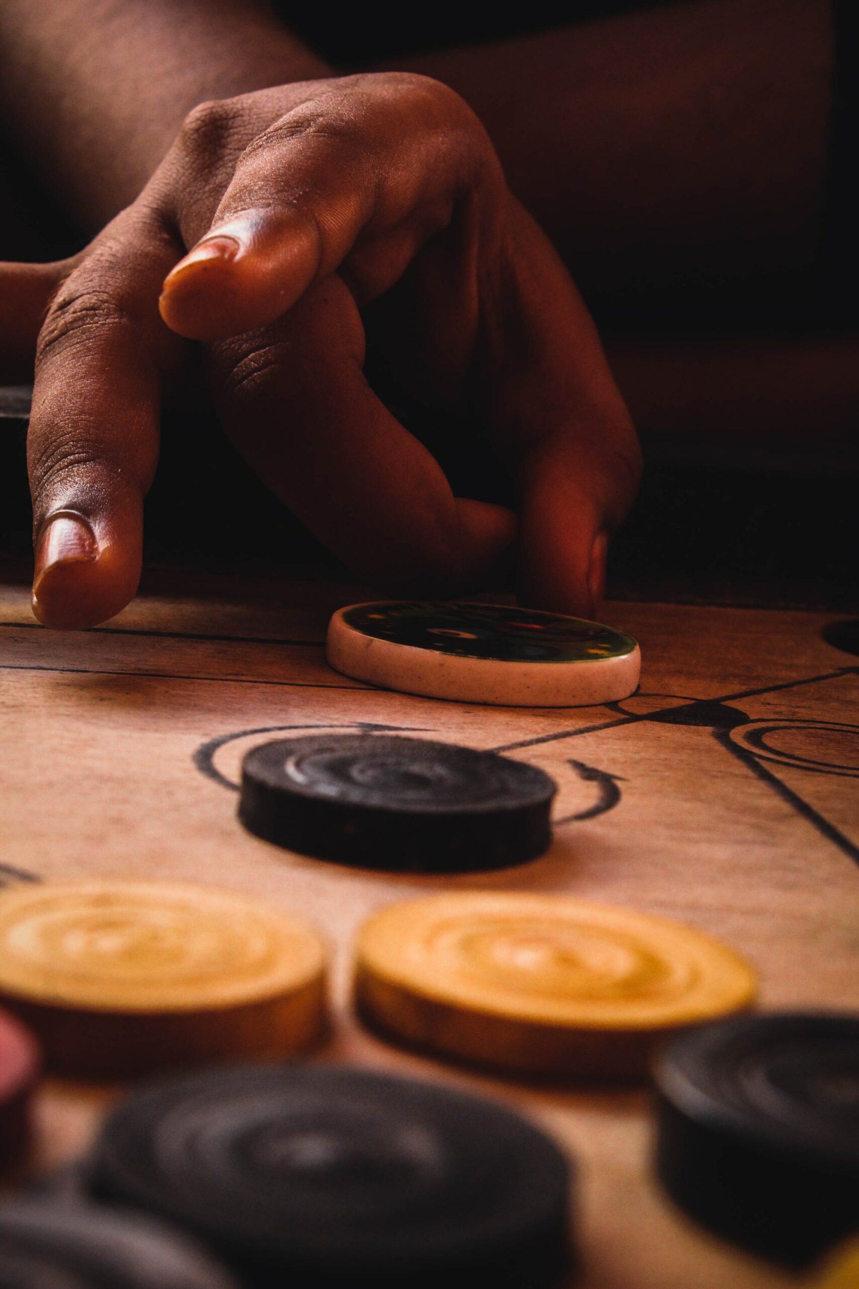 Photo of someone about to flick a carrom piece across the game board.