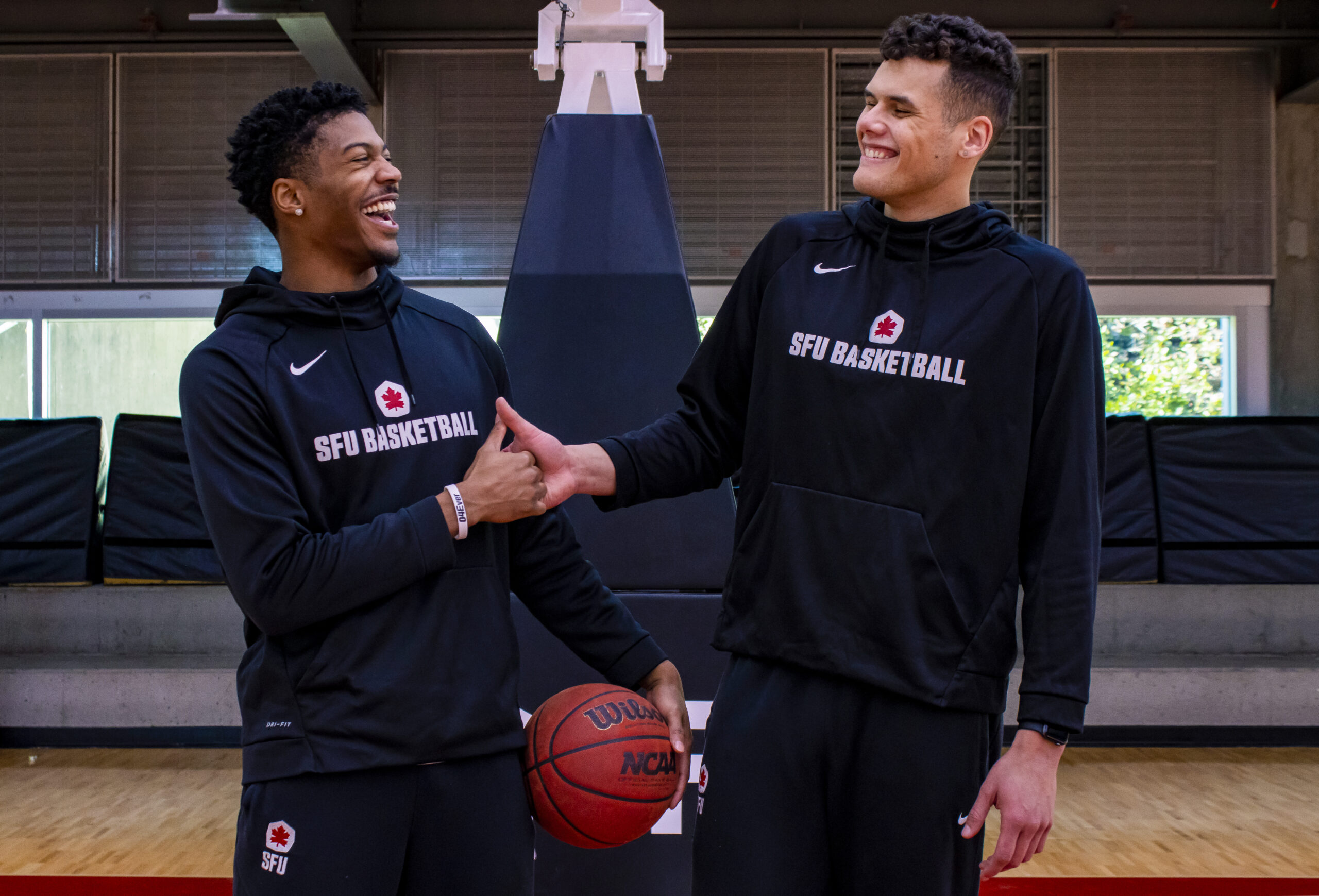 Seniors Jordan Lyons and Julian Roche giving each other a handshake while smiling at one another.