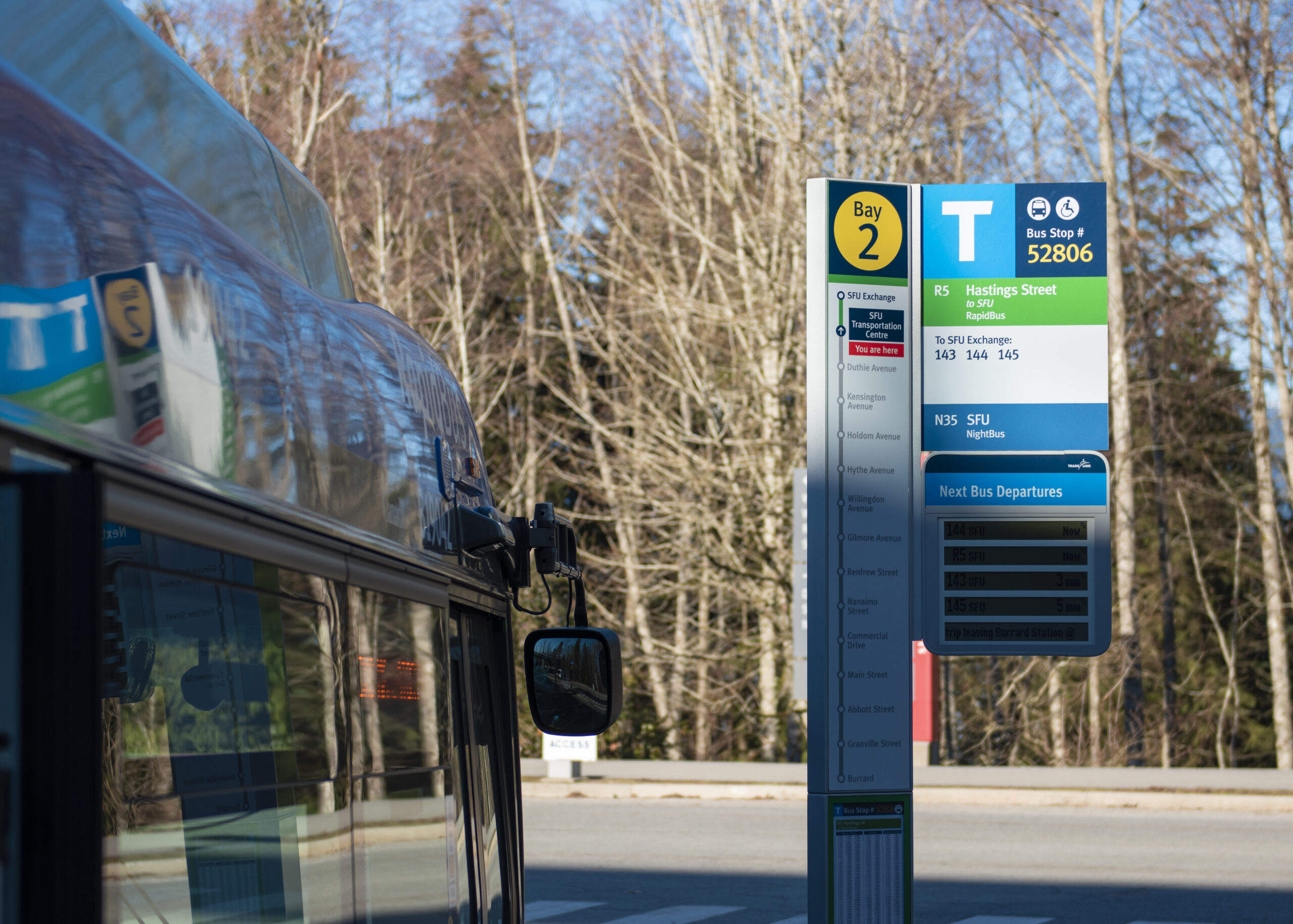 A photo of one of the bus stops at SFU. A bus is pulled up beside it. It looks like a nice day.