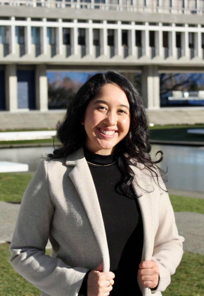 Pahou has served in various councillor and senate positions. Image courtesy of Helen Sofia Pahou Pahou is seen standing outside of the AQ located at SFU. She is smiling and looking directly at the camera.