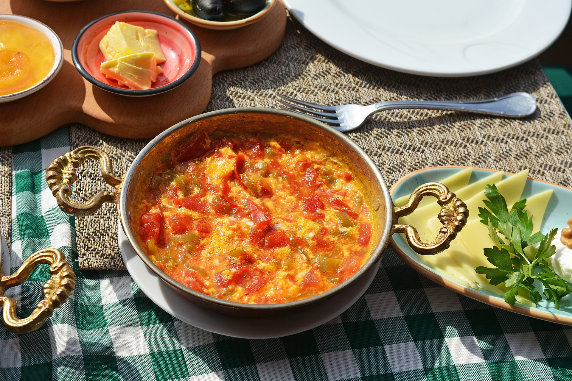 Skillet of menemen atop a table with a green and white checkered tablecloth