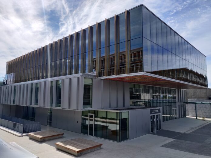 This is the second time in four years the Council has impeached a member. The SFU student union building can be seen. The sky behind is blue and cloudy. You can see the sky reflecting off the windows of the student union building.