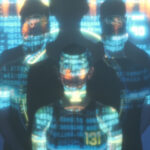 Controller fearlessly dives into the human-robot conundrum Three people stand facing different directions with blue code projected onto their bodies, and three shadows looming over them above