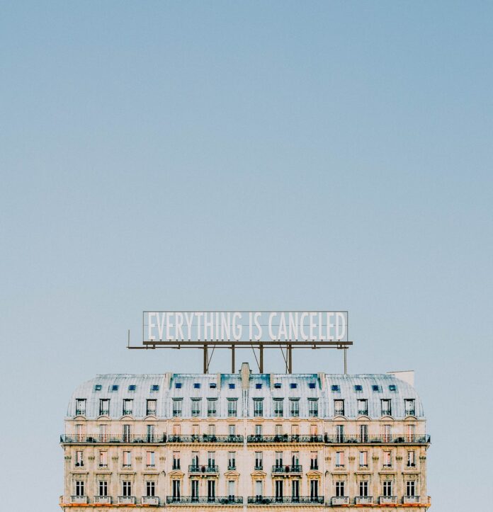 pexels-jeffrey-czum-4004291 row houses under a blue sky, with an “everything is canceled” banner above the homes.