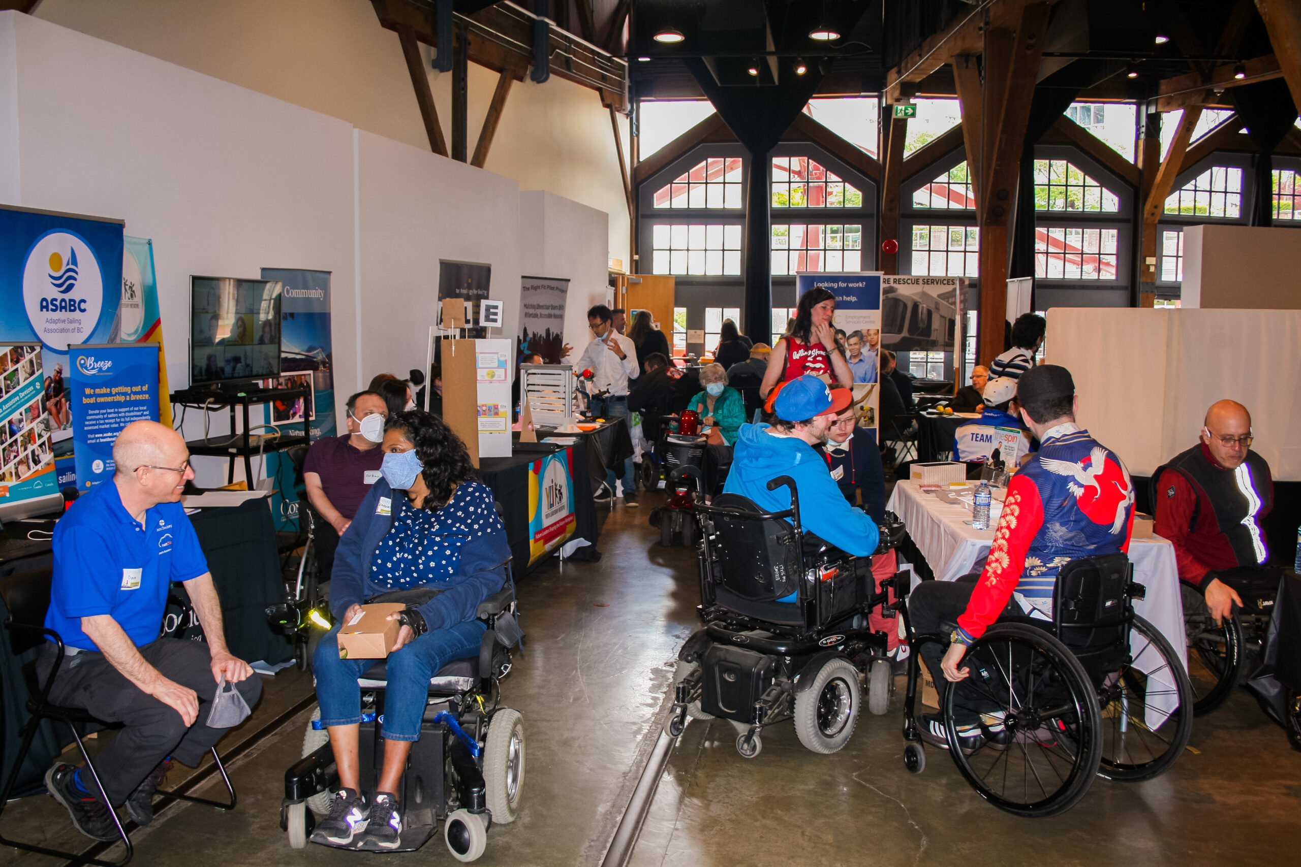 people in wheelchairs approaching vendors and the people stationed at them at the Abilities Expo 2022. Everyone appears to be genuinely connecting, with big smiles on their faces.