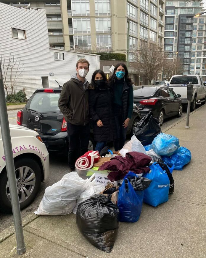 FB_IMG_1653109867911 Three members of ALAS stand in front of bags of clothing ready to be donated.