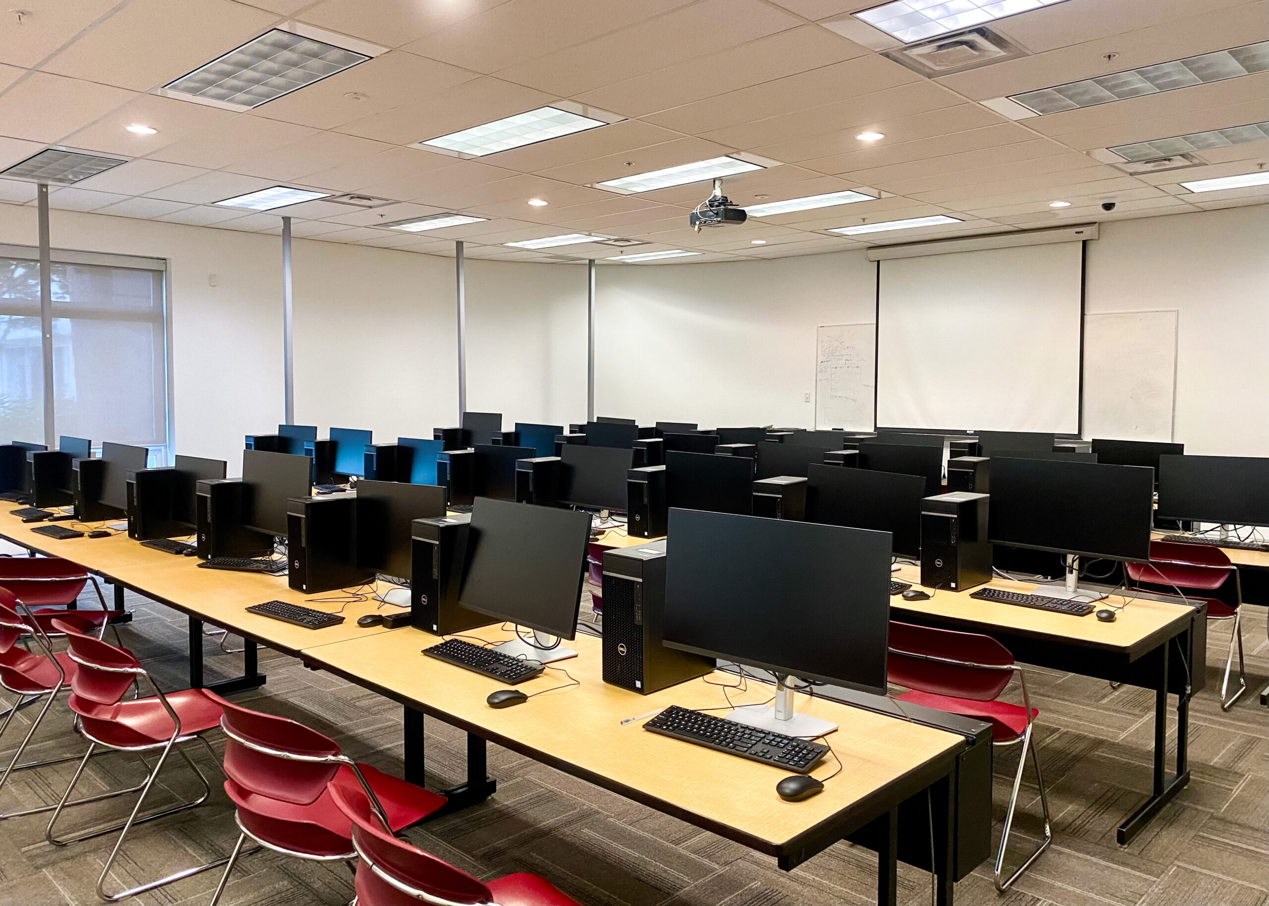 The photo is of the SFU computer lab. Rows of computers fill the room. The room has no people and the computers are all turned off.