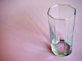 A photo of an empty glass on a pink bedsheet