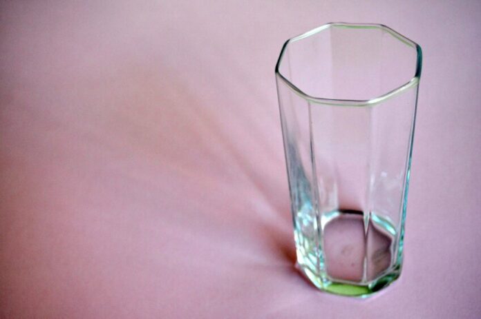A photo of an empty glass on a pink bedsheet