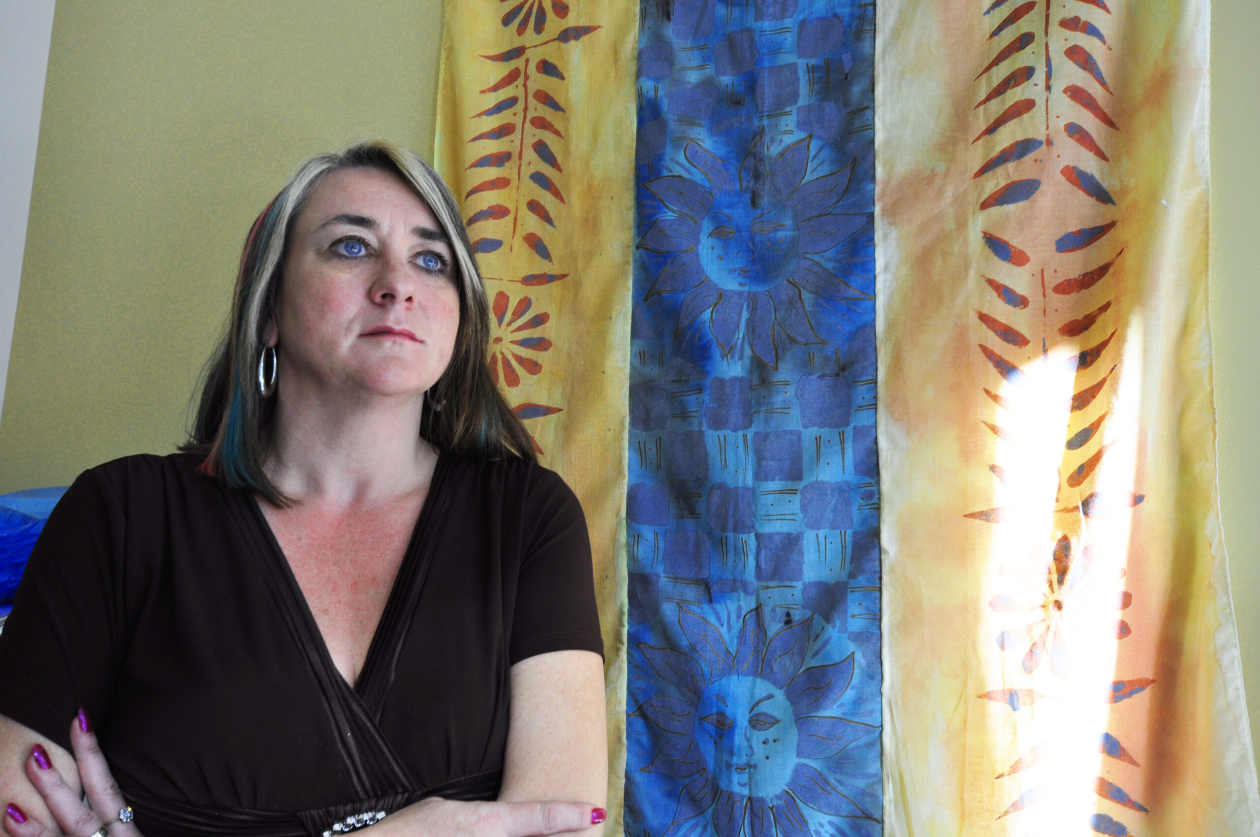 Dr. Jen Marchbank looking into the distance. She has shoulder length brown hair with two blonde streaks framing her face and a black v-neck top.