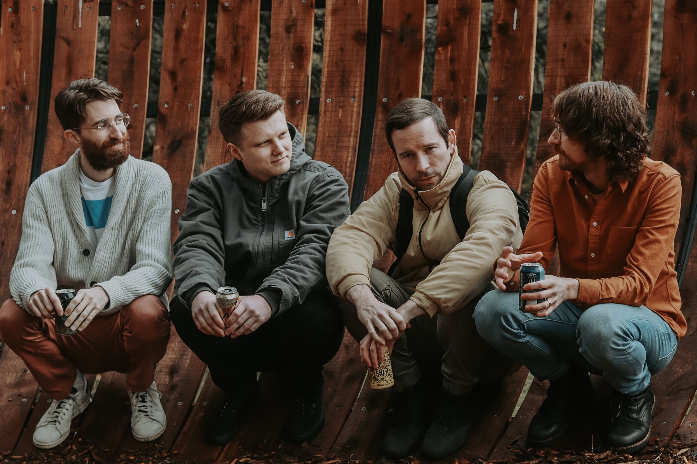 photograph of four band members crouched down together at a sidewalk.