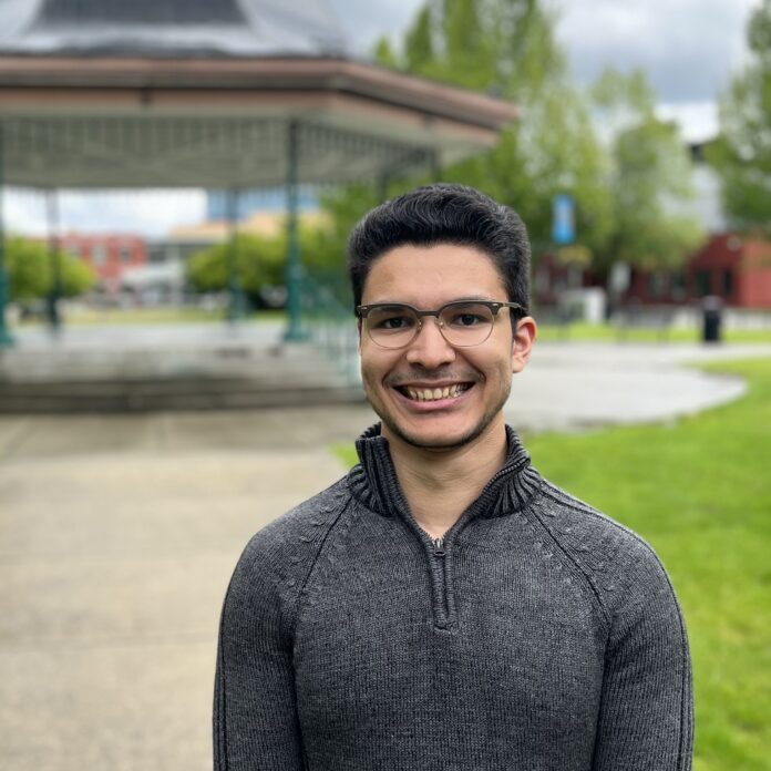 The photo is of Gabe Liosis. It is a headshot of Liosis where he is staring into the camera and smiling.